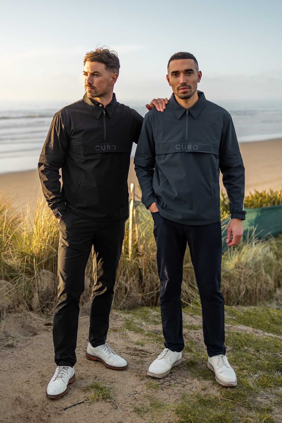Two golfers wearing the Curo Cadence Windshirt
